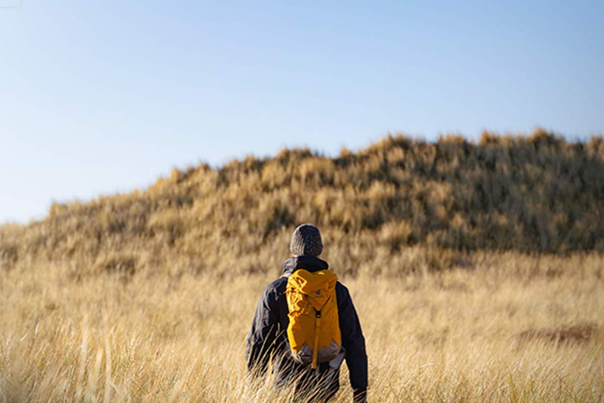 pessoa a passear num campo com mochila às costas