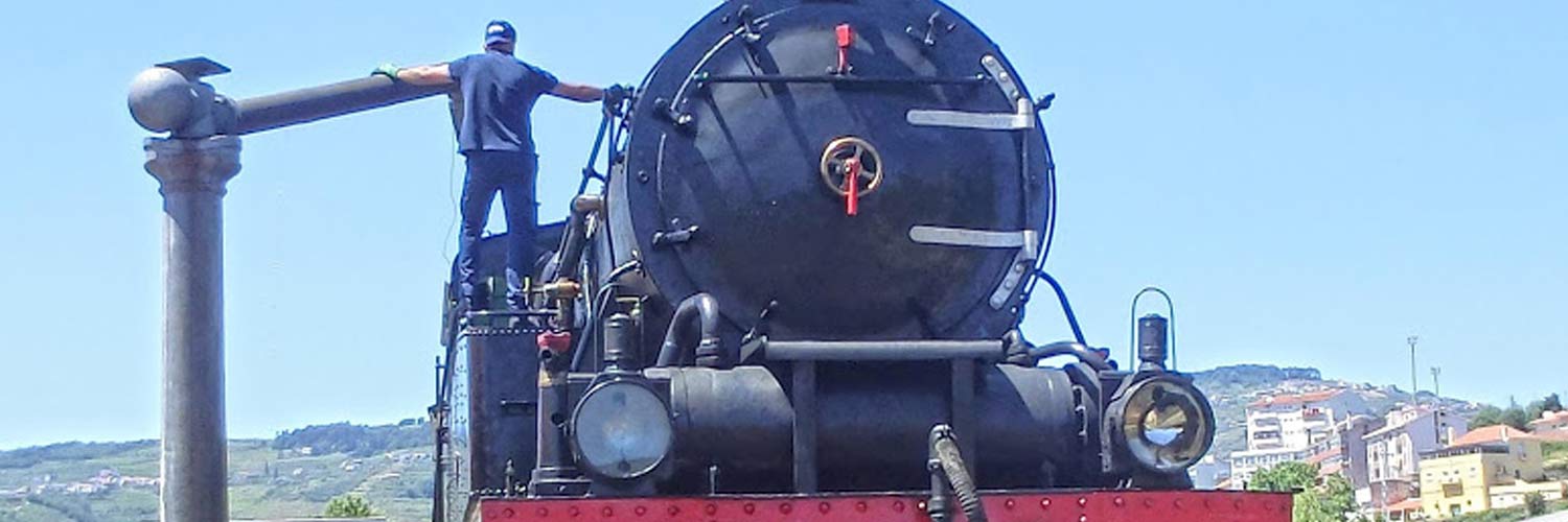 Pormenor do alto da locomotiva a vapor com senhor da tripulação na operação de abastecimento de água. 