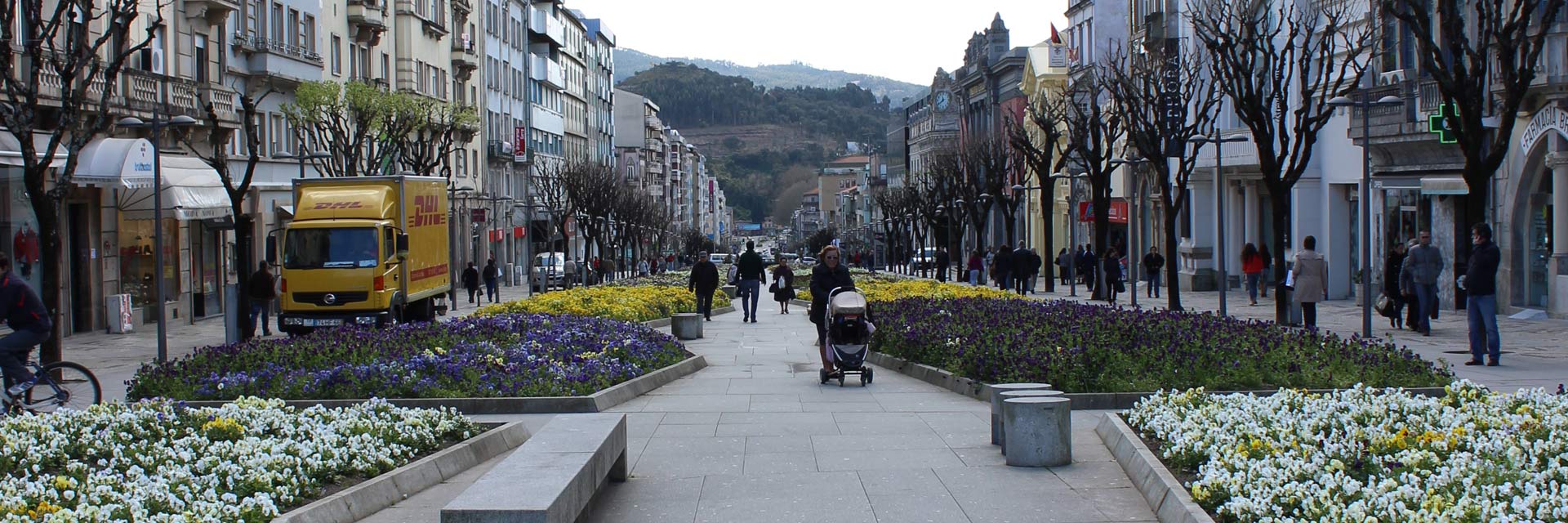 Avenida da Liberdade, via pedonal da cidade, com vários canteiro floridos e pessoas.