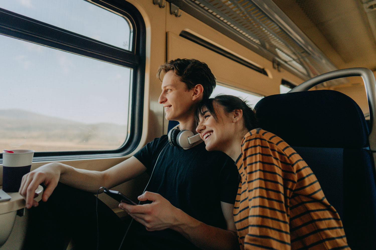 Casal jovem a rir e a olhar pela janela do comboio.