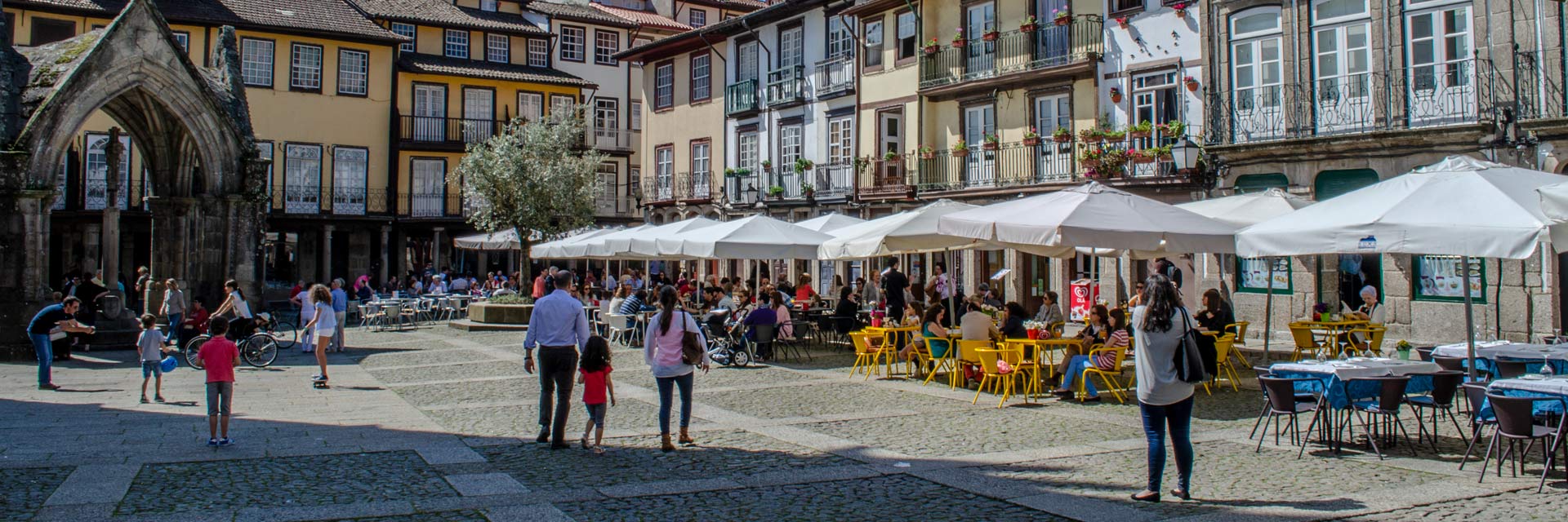 Largo da Oliveira no centro histórico com casas típicas, esplanadas e o Padrão de Nossa Senhora da Vitória.