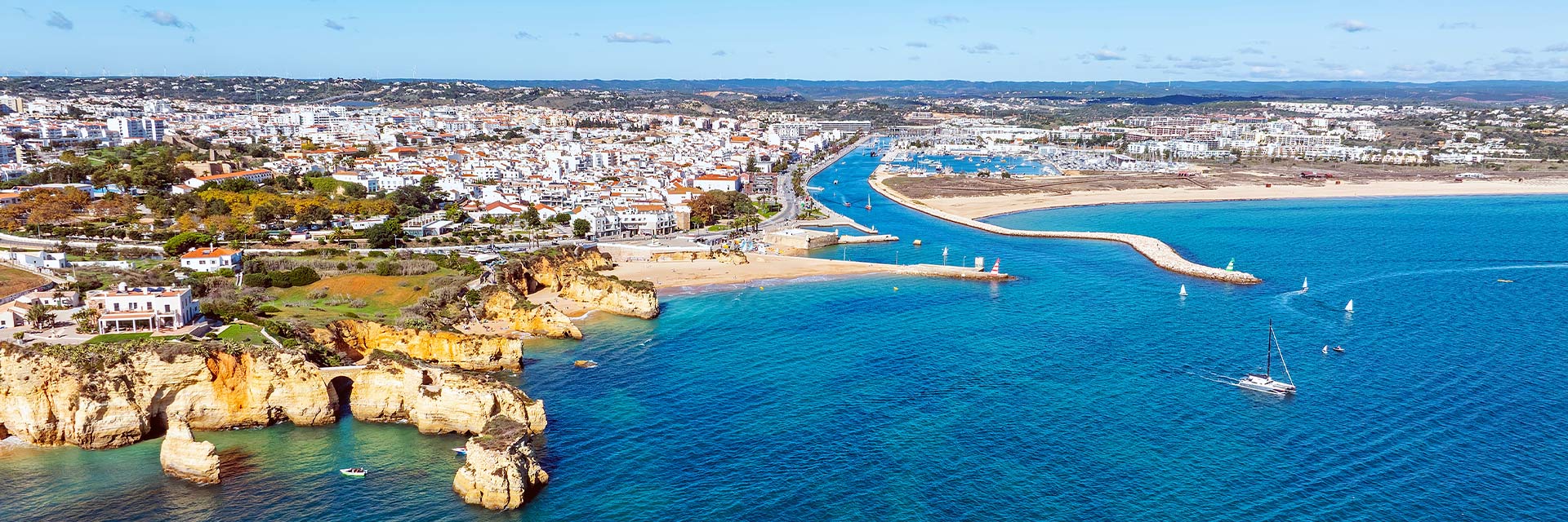 Vista aérea sobre Lagos, com praia e prédios junto à costa marítima.