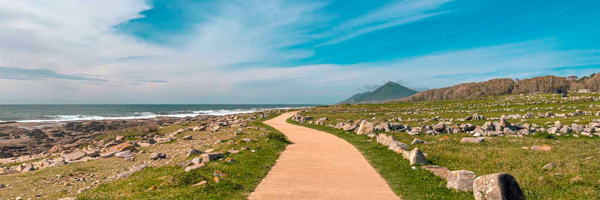 Ciclovia junto ao mar e campo, com relva e pedras, na região do Minho.