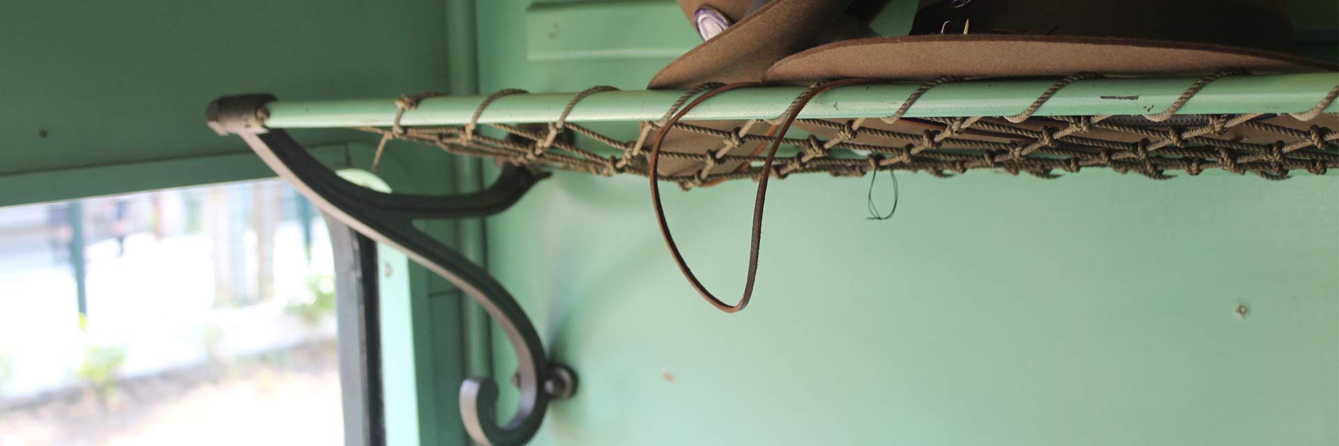 Interior de carruagem histórica: detalhe do suporte em metal e corda, que fica por cima dos bancos, para pequenas bagagens.