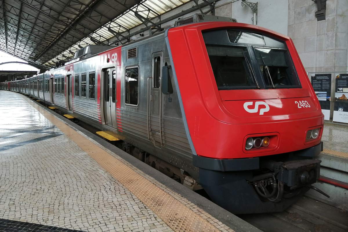 Automotora elétrica da série CP 2400 cor vermelho e cinzento, parada numa das plataformas da estação.