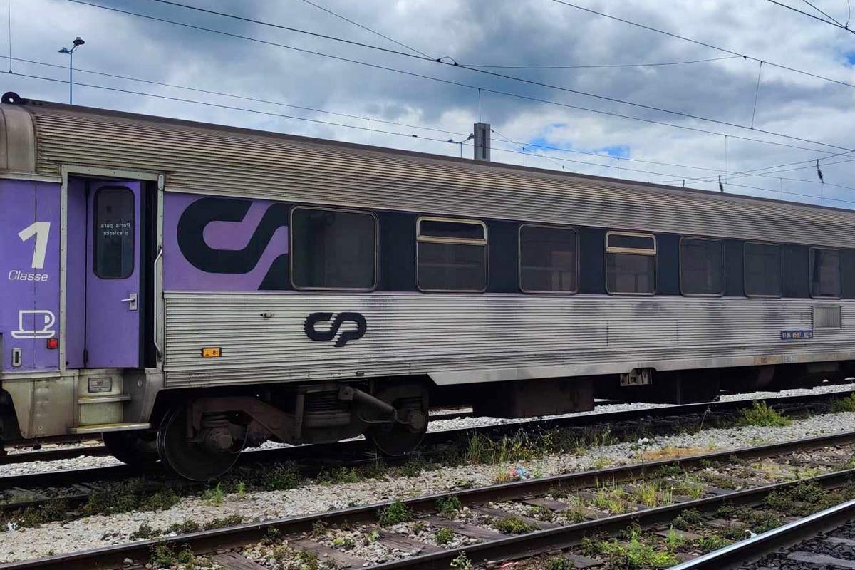 1st class Sorefame coach with purple and gray livery stopped at one of the station lines.