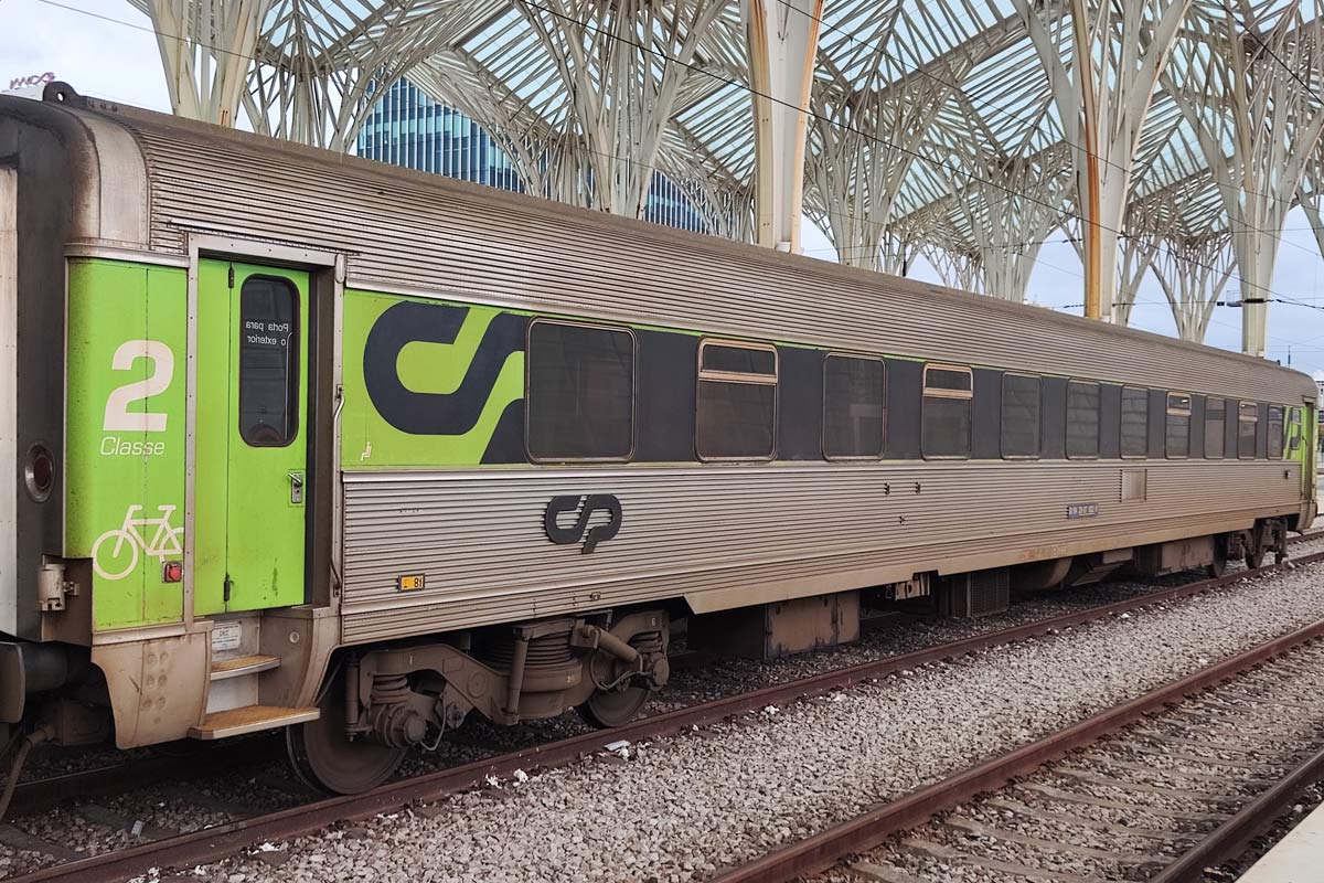 2nd class Sorefame coach with green and gray livery stopped at one of the station lines.