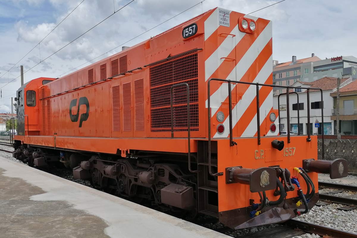 CP 1550 series diesel locomotive with orange livery and white stripes at de front stopped in one of the station lines.