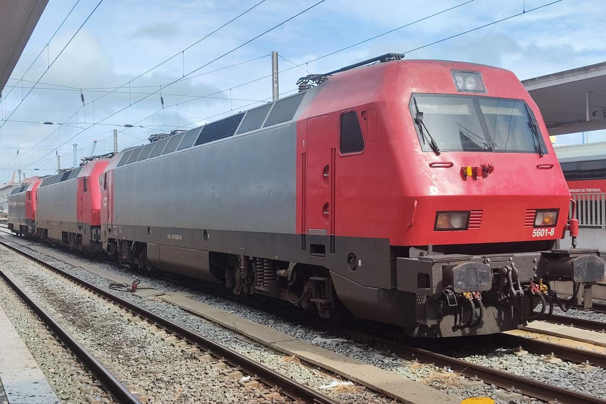 Three electric locomotives from CP 5600 series with gray and red livery parked one of the station lines.