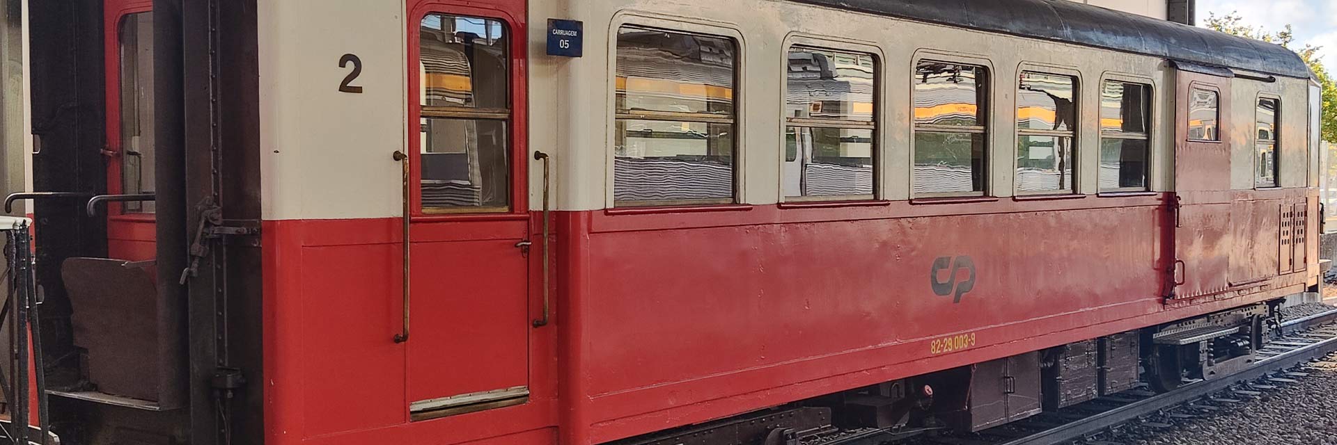 Aeyf 26 narrow gauge passenger coach with red and white livery stopped at the station.