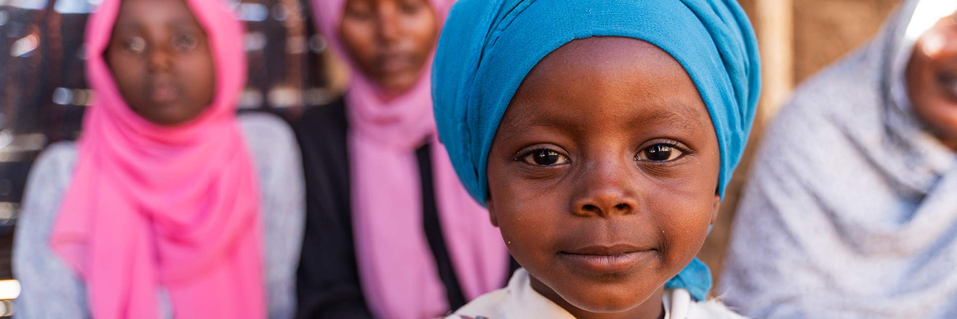 Criança do Chade com turbante com outras crianças ao fundo