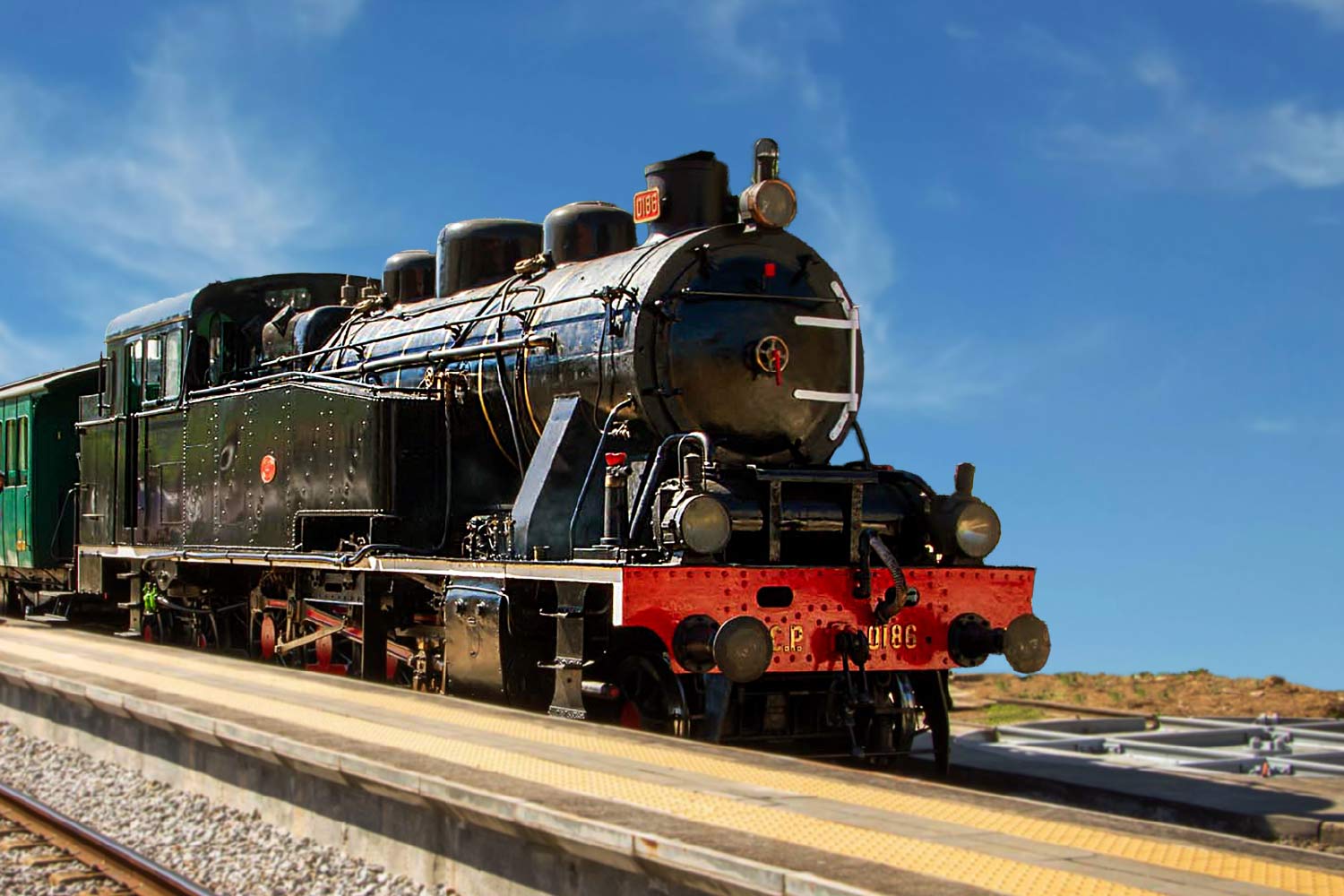 Imagem a cores da locomotiva a vapor CP 0186, cor preto e vermelho.