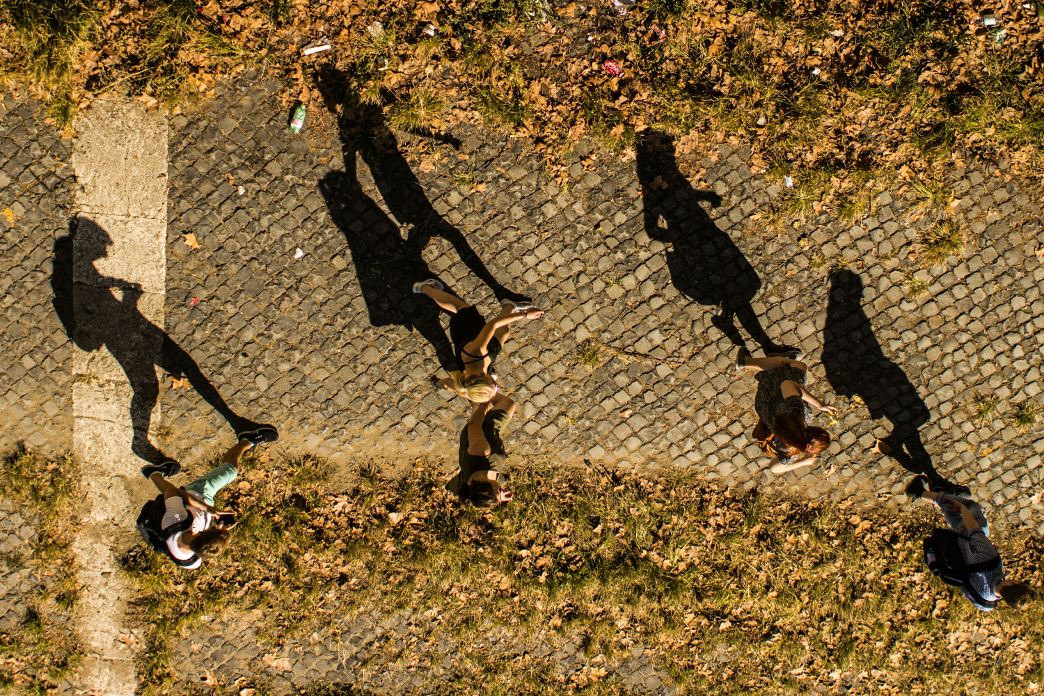 People walking with their shadows reflected on the ground.