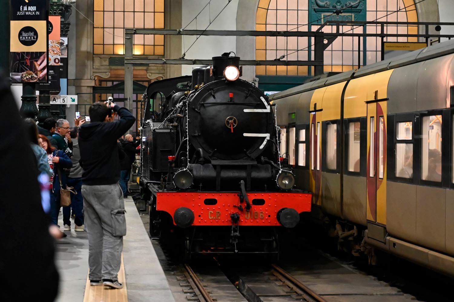 Pessoas na plataforma da estação junto da locomotiva a vapor.