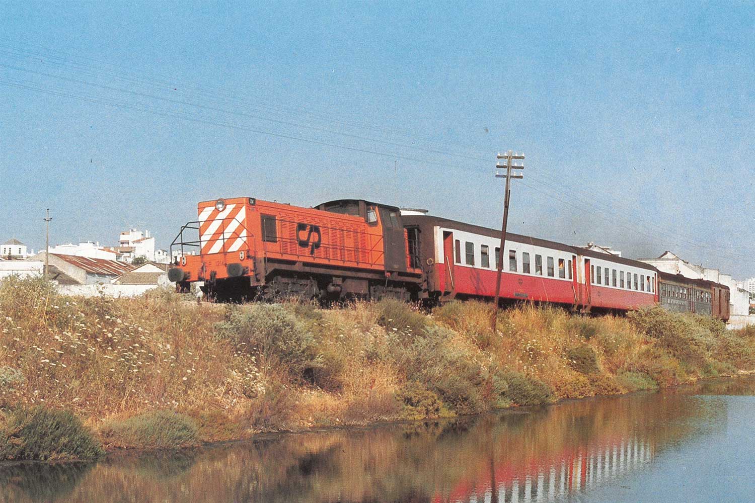 CP 1200 series diesel locomotive with two red and white coaches, a grey coach and a red van.