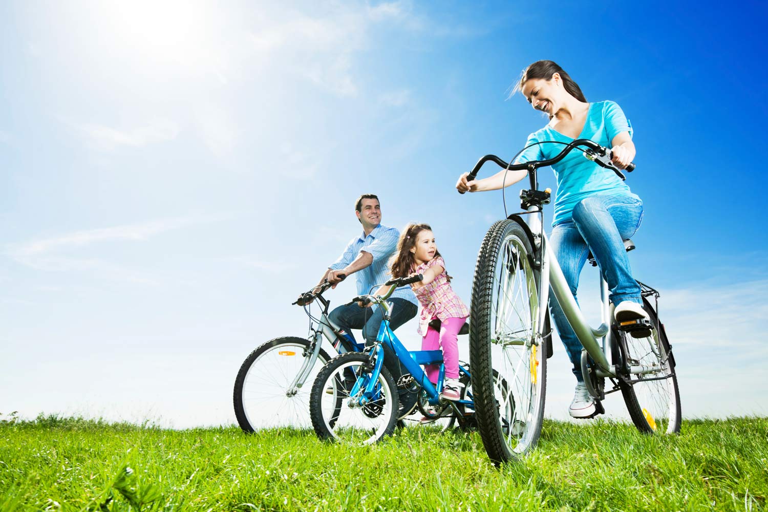 Mãe, pai e filha, a andarem de bicicleta.