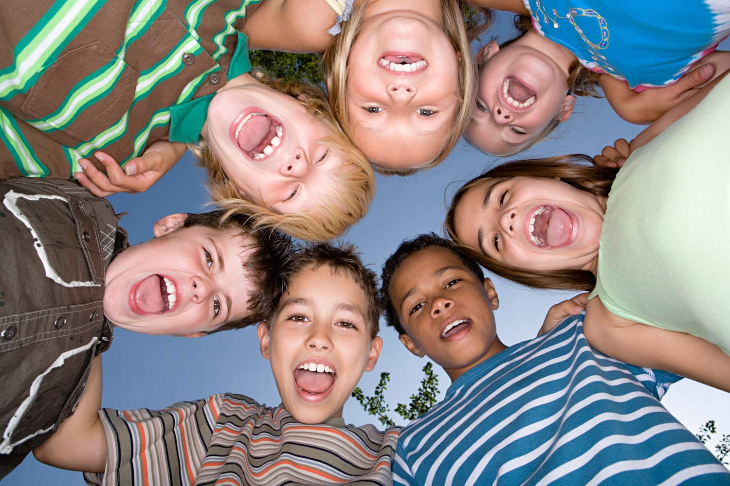 Crianças com cabeças encostadas em círculo.