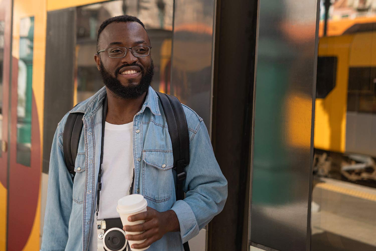A young smiling person standing next to a Porto urban train at a station
